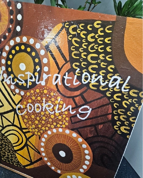 Inspirational Cooking in white letters over the top of Aboriginal artwork with 